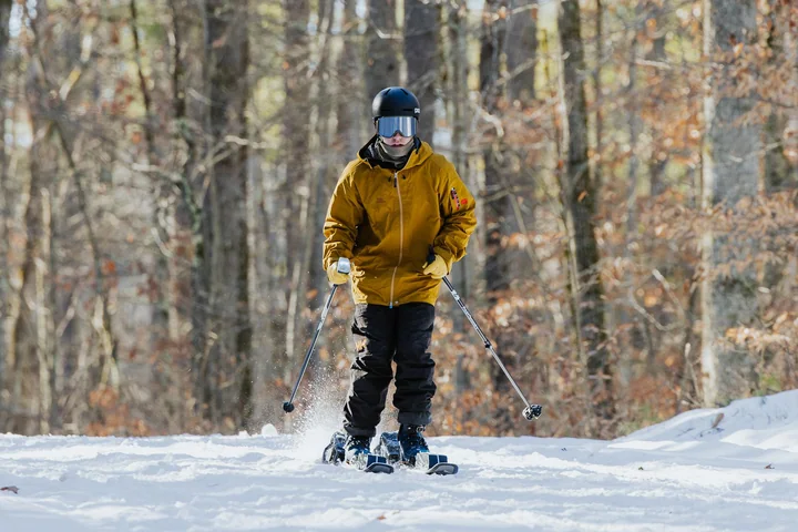 A rider on Frigid Dynamics E-XC electric skis on a groomed forest trail